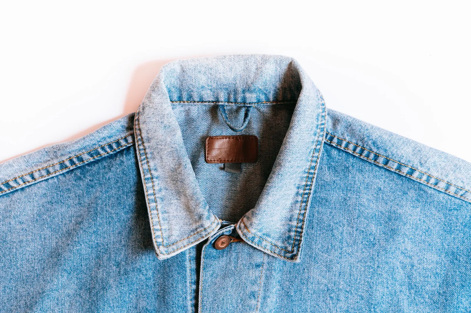 A worn denim workwear jacket showing faded seams and hardware