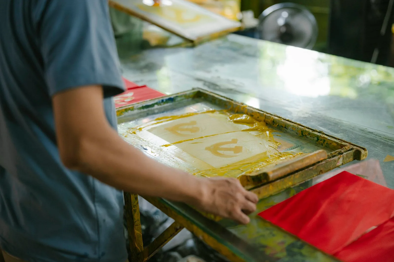 A squeegee pulling ink across a screen onto a shirt