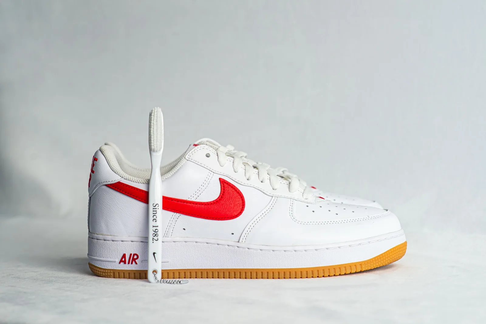 A brush being used to clean the side of a white sneaker