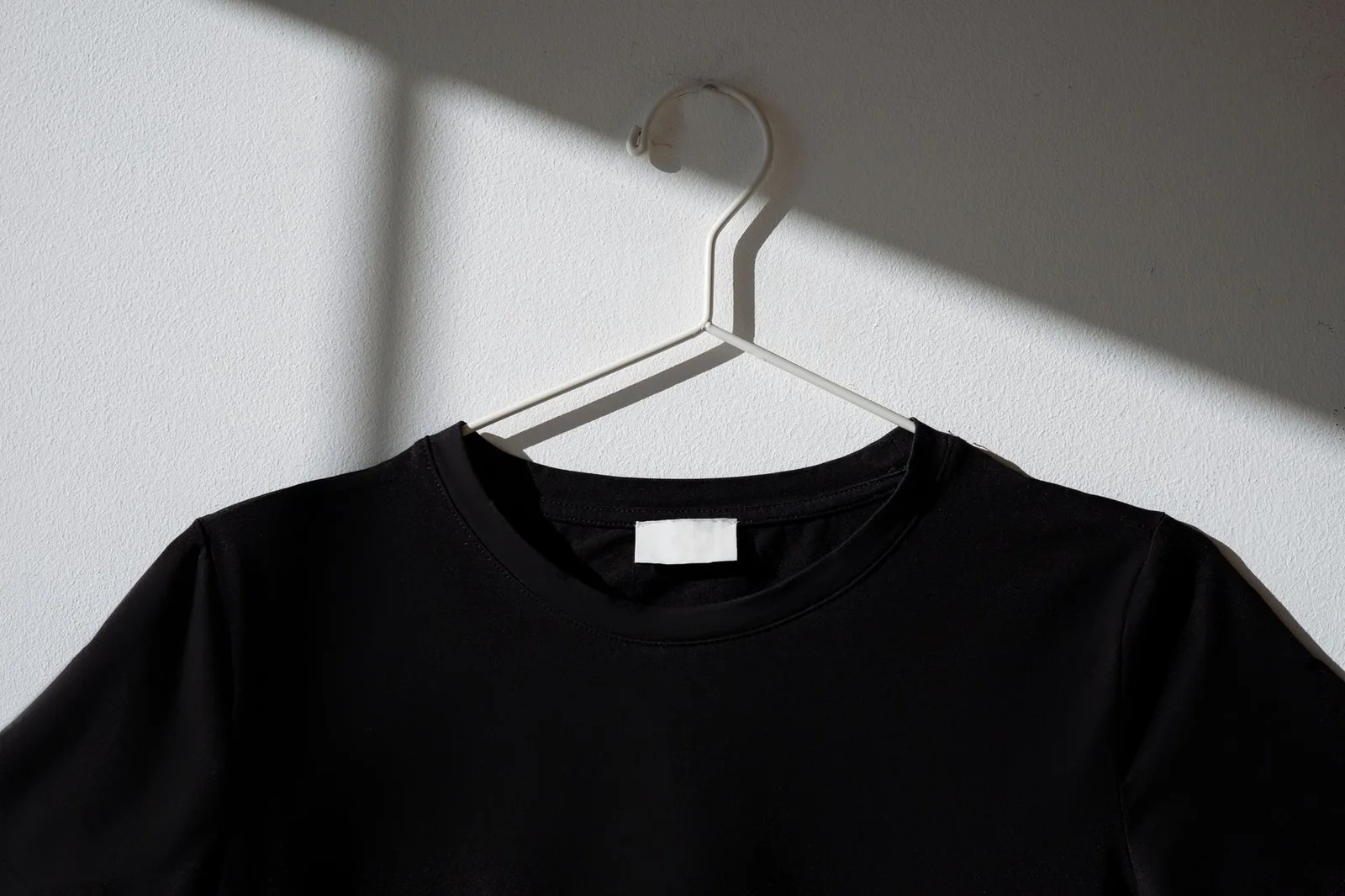 Plain T-shirts in neutral colors hanging on a rail